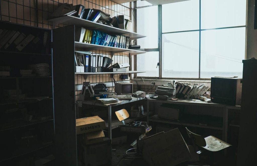An extremely cluttered office space with old computers on tables