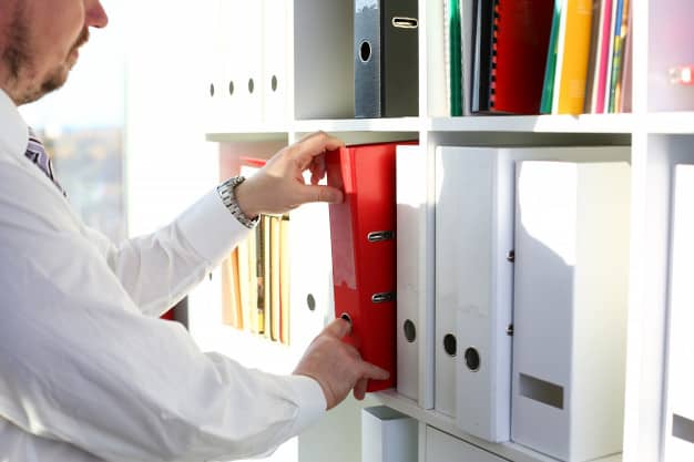 male pick red file folder from office book shelf