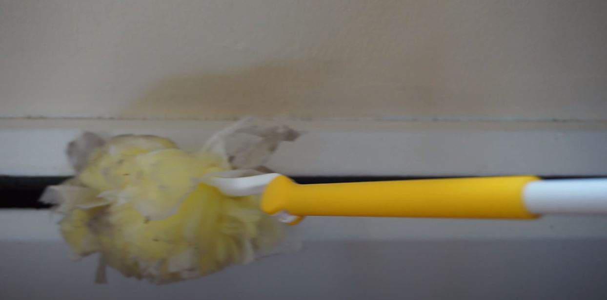 a yellow feather duster cleaning skirting boards