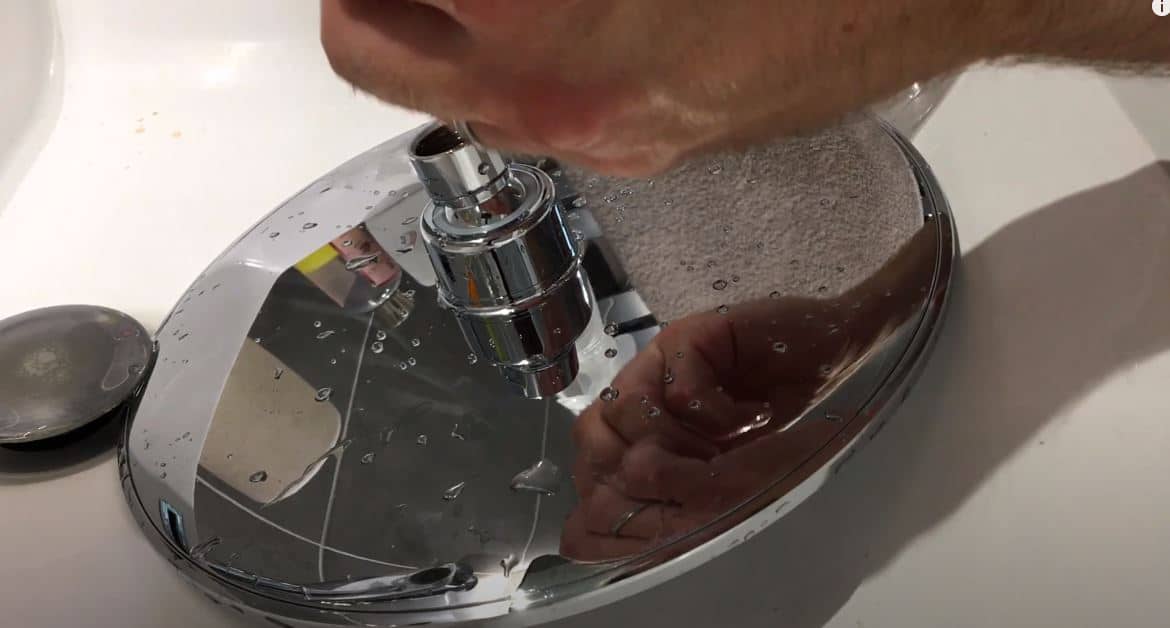 cleaning a rainfall shower head in a white basin