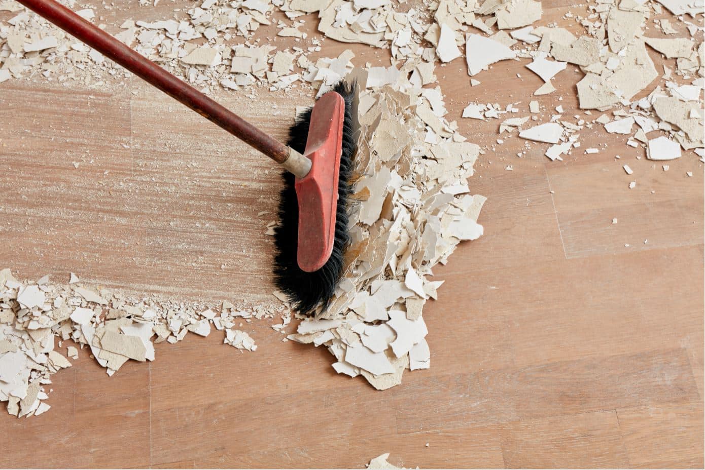 Person sweeping construction debris with a red broom with black bristles