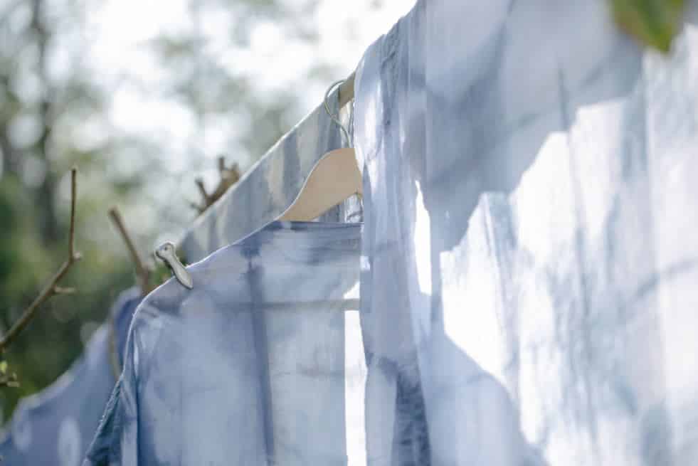 three blue business shirts hanging on a clothesline