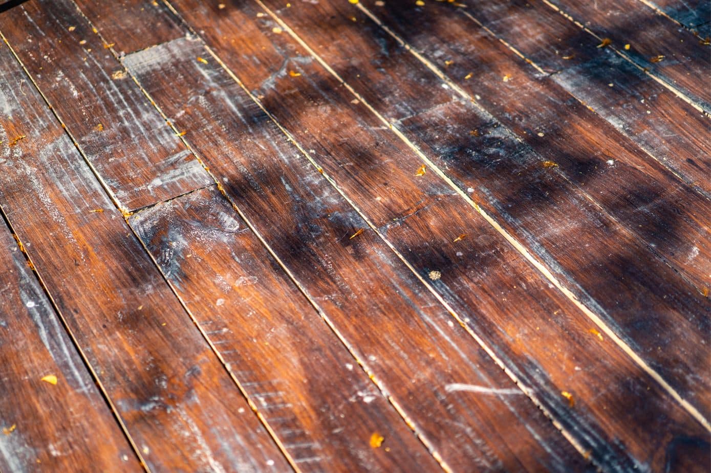 old worn timber floorboards with white marks that have been damaged by the elements