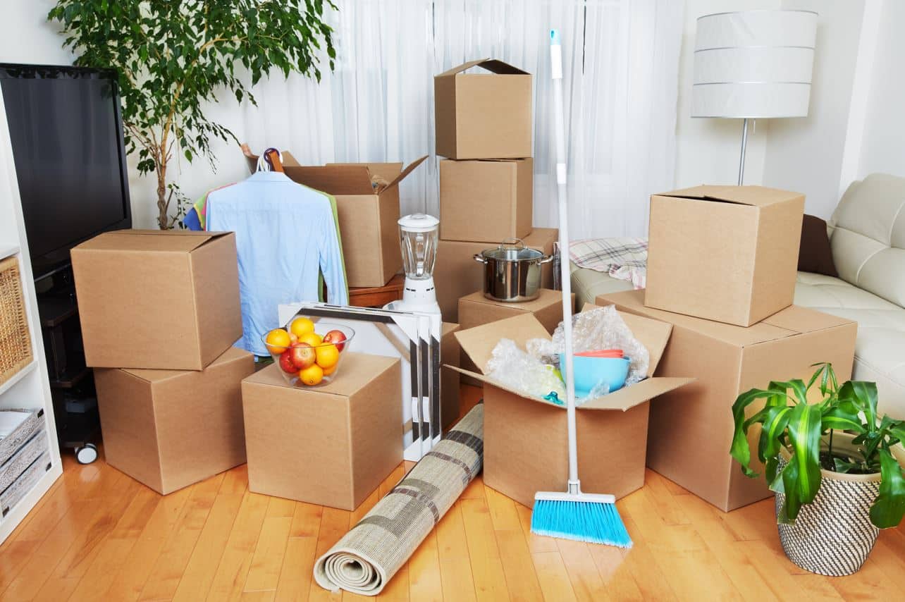 moving boxes on a wooden floor in a large living room with other assorted items packed together